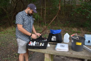 Volunteer water quality monitor preparing monitoring kit on a picnic table